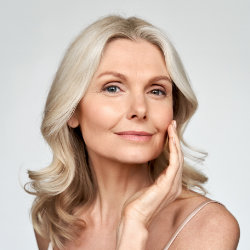 Happy youthful mature woman touching her cheek.