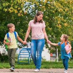 A woman walking with her son and daughter to school.