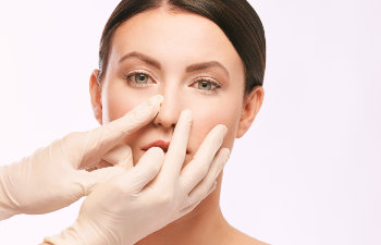 Plastic surgeon touching a nose of a woman considering nose job.