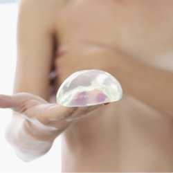 A woman holding a breast implant.